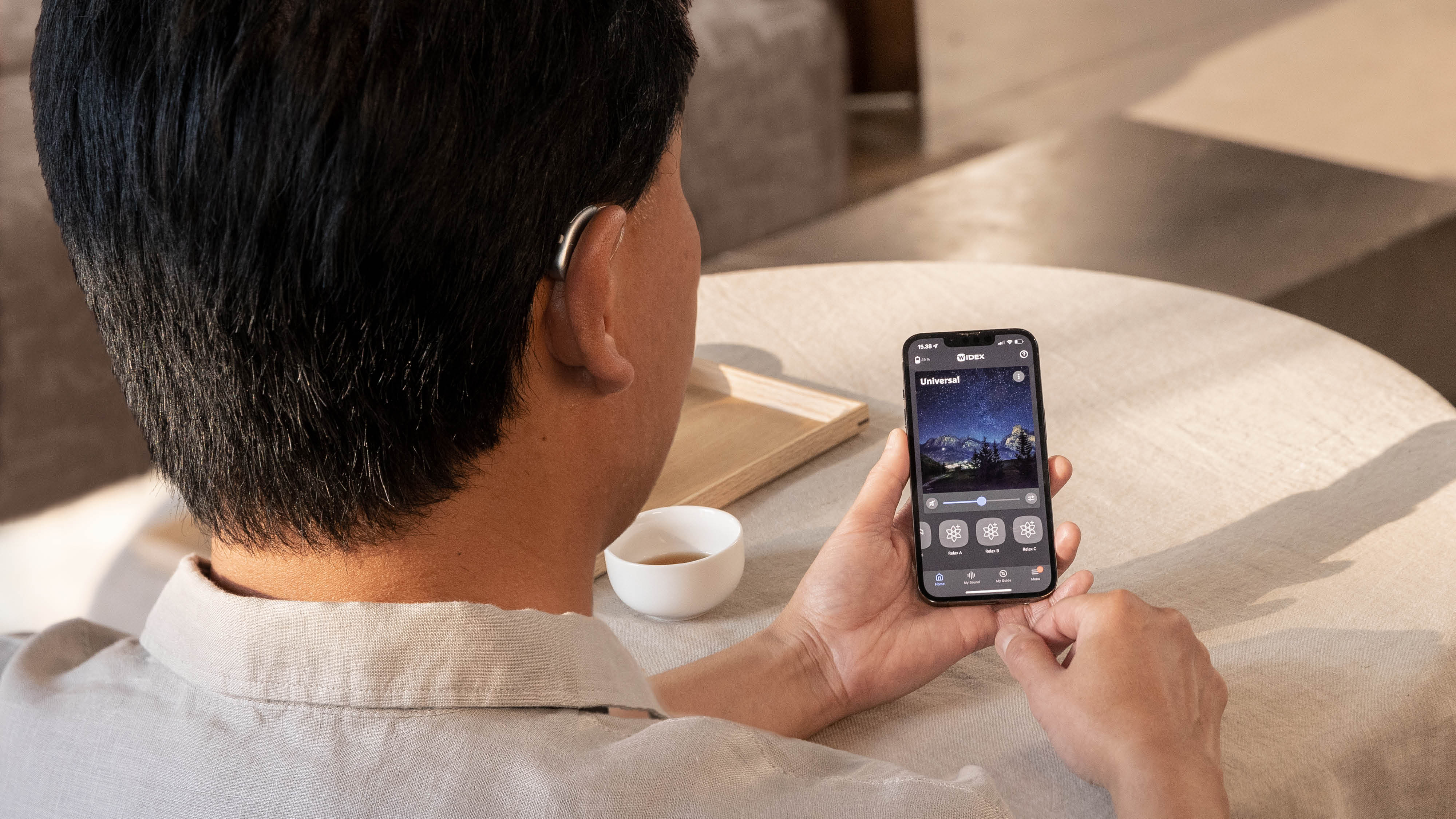 Träger von Widex Moment Hörgeräten steuert seine Hörgeräte über Moment App